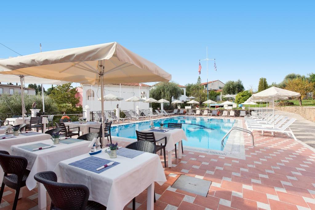 a hotel with a pool with tables and chairs at Marietta's Resort by Konnect, Gouvia Corfu in Gouvia