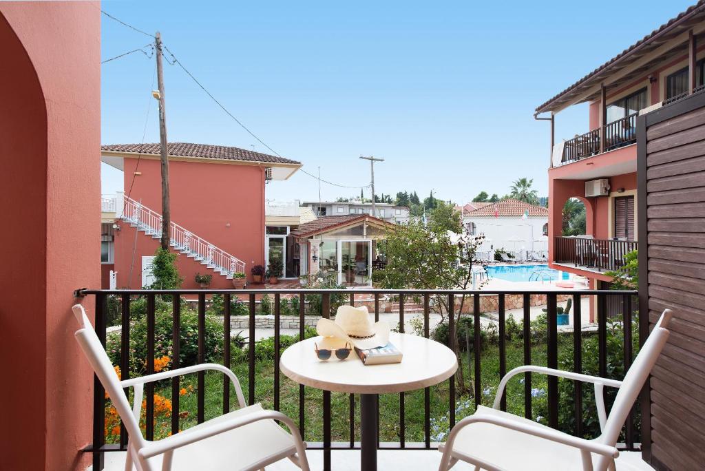a balcony with a table and chairs and a pool at Marietta's Resort by Konnect, Gouvia Corfu in Gouvia