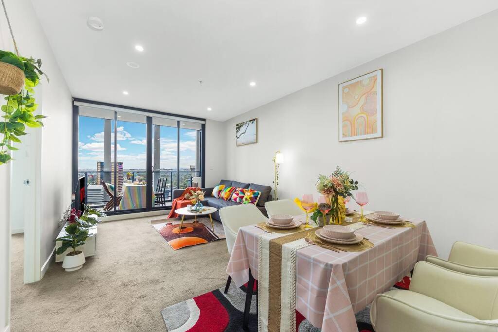 uma sala de estar com uma mesa e um sofá em Sky-City Apt 3 min to Train & Shopping& Everything em Sydney
