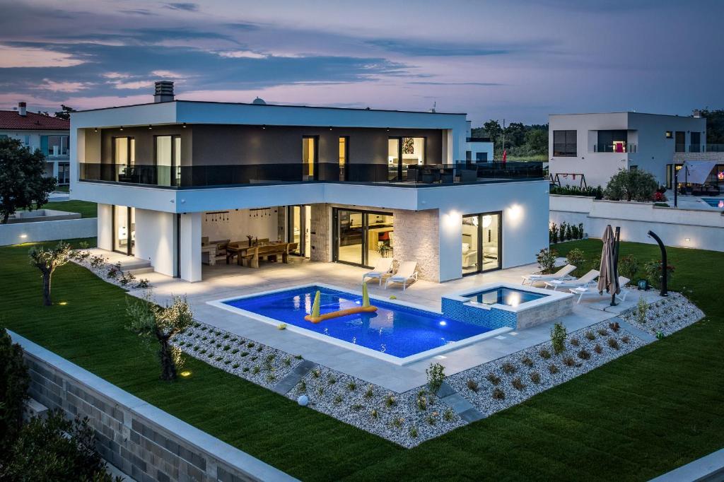 een groot huis met een zwembad in de achtertuin bij Villa MaEm in Central Istria for families with Sauna, Whirlpool & Sea View in Juršići