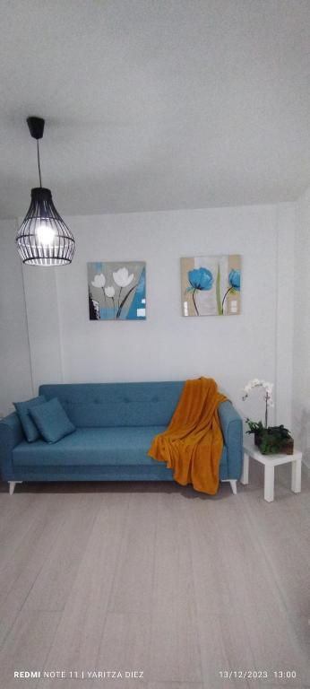 a living room with a blue couch and some paintings at PisoYari in Santa Cruz de la Palma