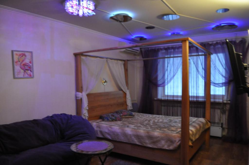 a bedroom with a canopy bed and a couch at Cozy apartments near the McDonalds in Kremenchuk