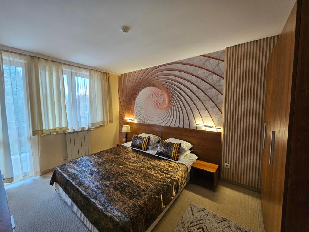 a bedroom with a bed with a painting on the wall at Enjoy Studio and Lovely Apartment Villa Park in Borovets