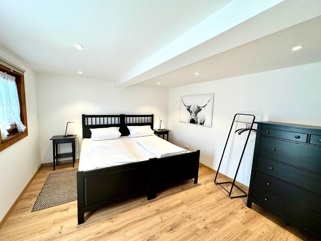 a bedroom with a black bed and a dresser at Ferienwohnungen Roderer in Berchtesgaden