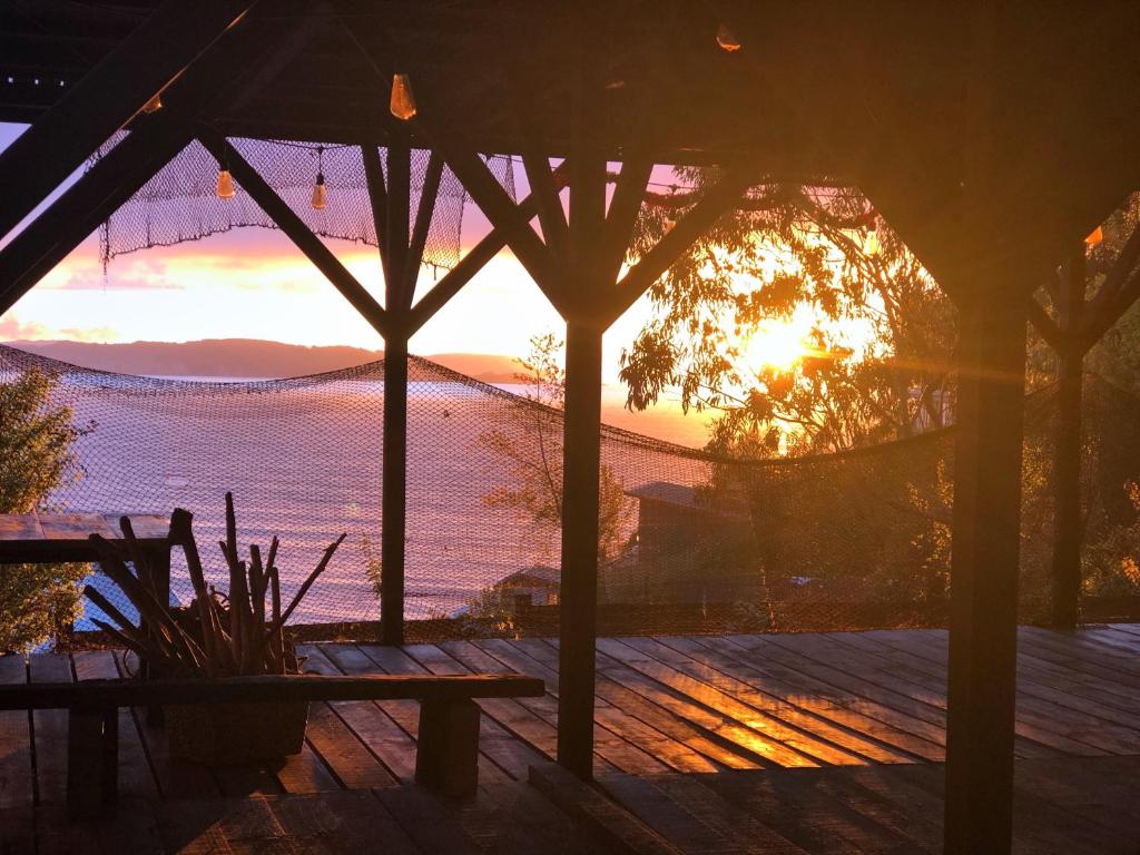 una puesta de sol desde el porche de una casa con un banco en Alojamiento Concepción, Tomé, Cocholgüe en Concepción