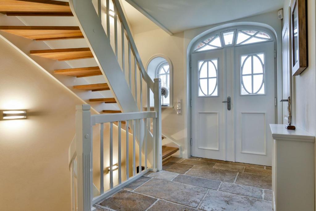 a hallway with a white door and stairs at Keitum Royal in Keitum