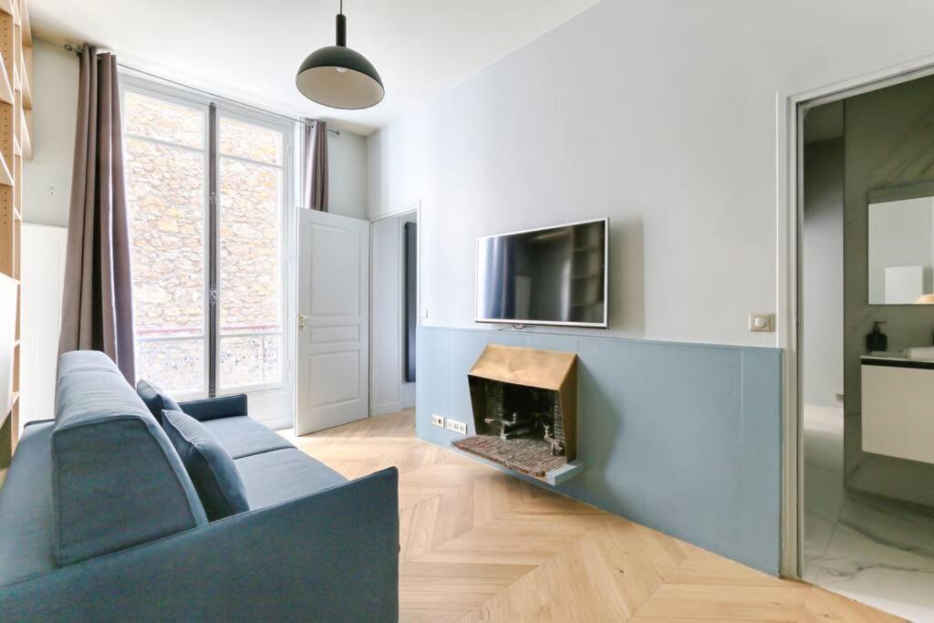 een woonkamer met een blauwe bank en een open haard bij Champs Elysées Marbeuf Magnifique Appartement 4P in Parijs