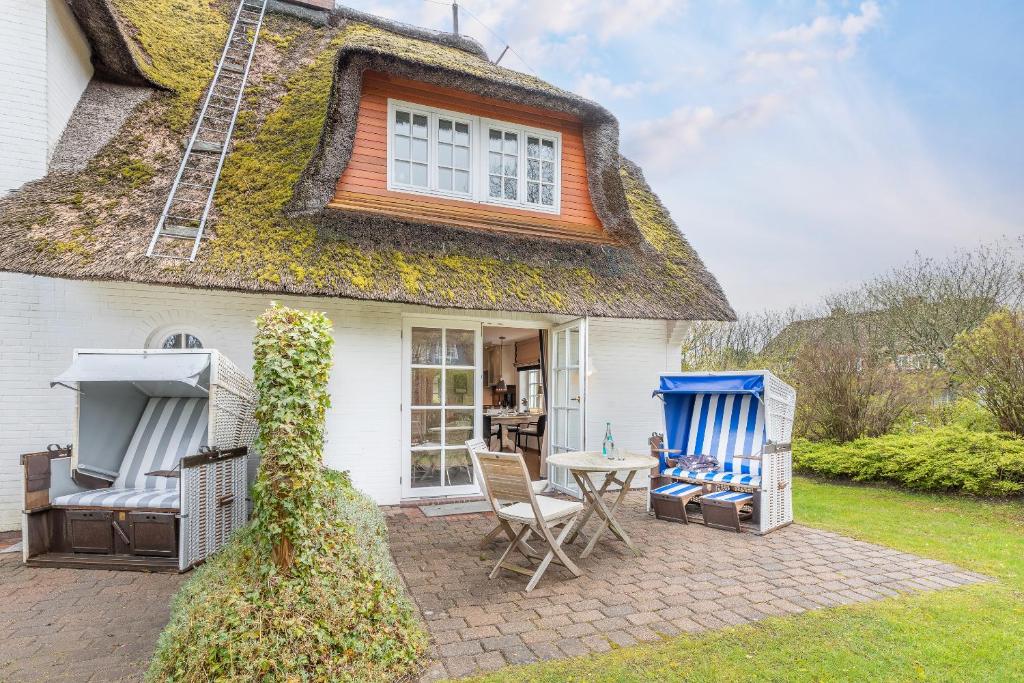 a cottage with a thatched roof with chairs and a table at Suederhof 6 in Keitum