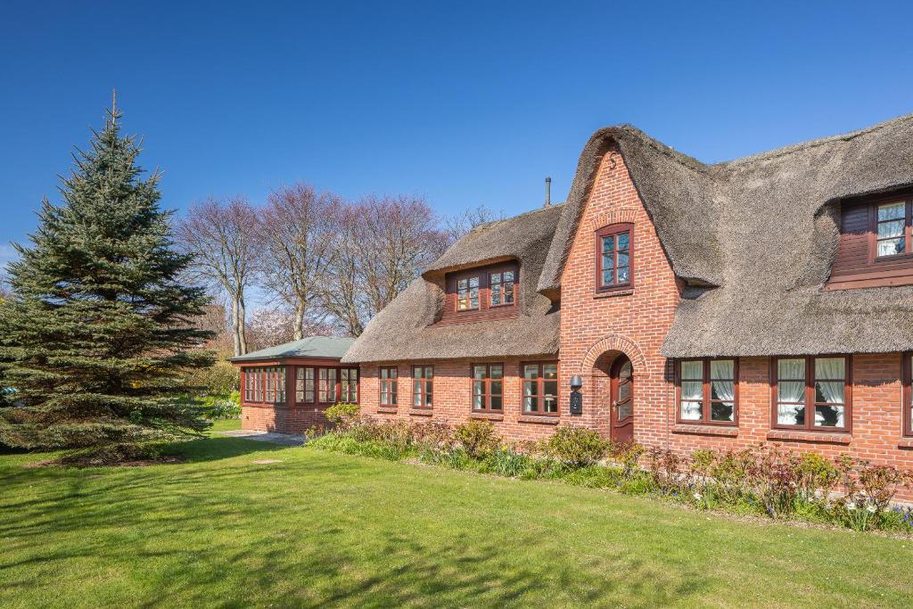 a large brick house with a thatched roof at Aalernhues in Keitum
