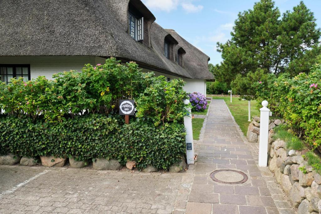 a house with a thatched roof and a walkway at Sharky Bay in Keitum