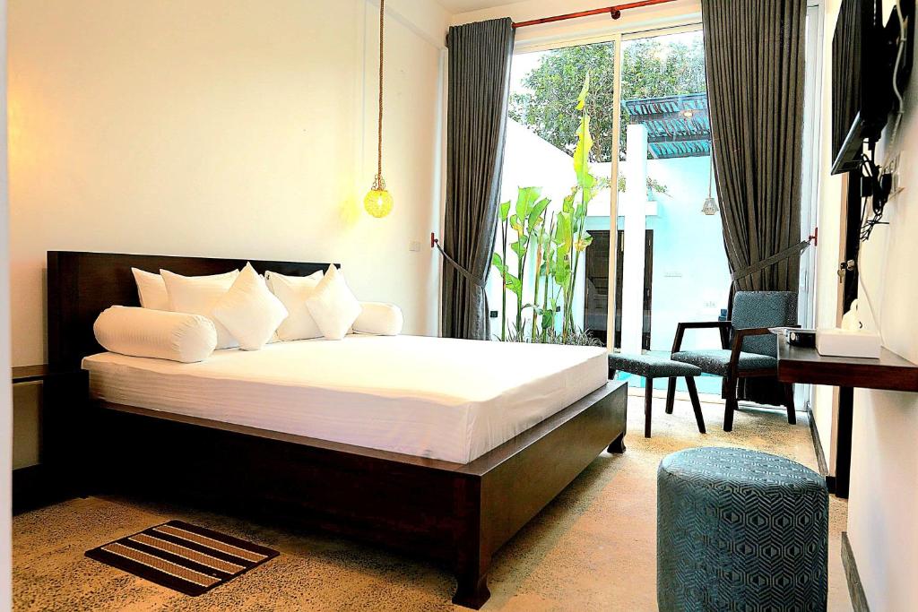 a bedroom with a bed with white sheets and a window at Private Pool Cabanas AC - Angam Villas Hikkaduwa in Hikkaduwa