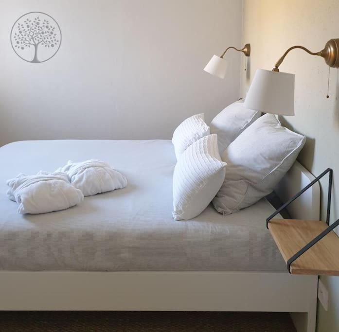 a white bed with white pillows and a lamp at Guest house avec spa Jura , gîte du petit pommier 