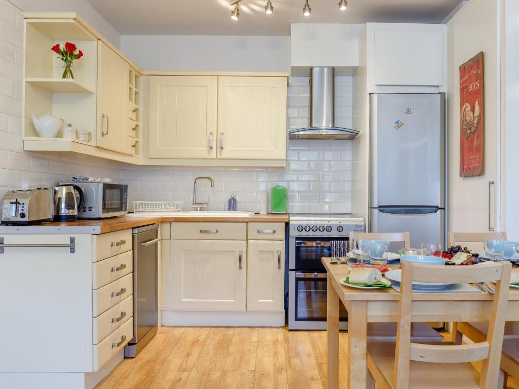 a kitchen with white cabinets and a table and a refrigerator at 2 Bed in Brixham 80008 in Brixham