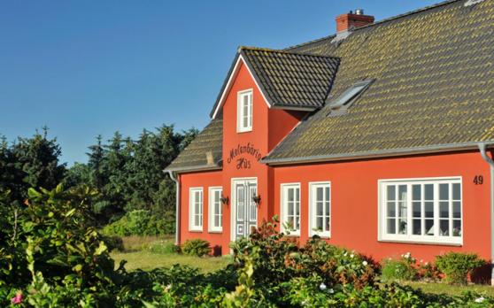 una casa roja con techo negro en Melenbarig Hues, en Munkmarsch