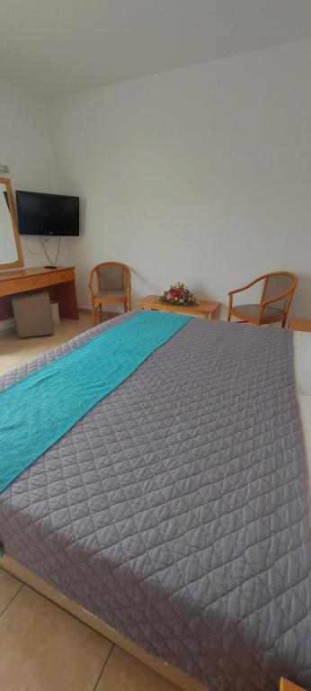a large bed in a room with two chairs and a tv at New Famagusta Hotel & Suites in Ayia Napa