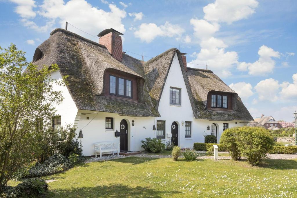 une maison blanche avec un toit de chaume dans l'établissement Suederwind 2, à Keitum