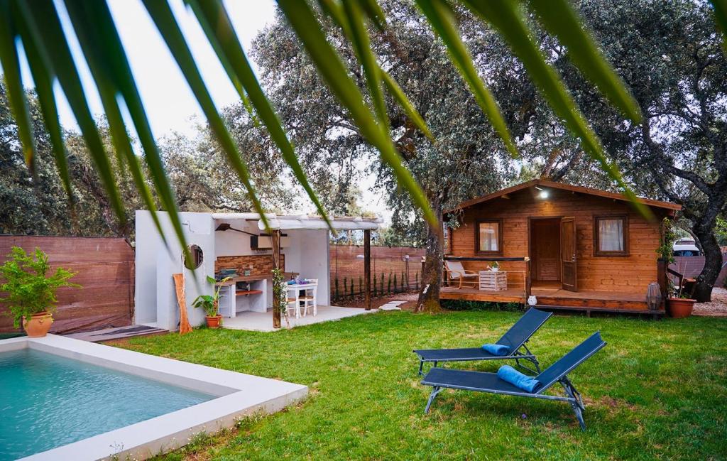 een tuin met een zwembad en een stoel en een huis bij Villa Experience Rural in Ronda