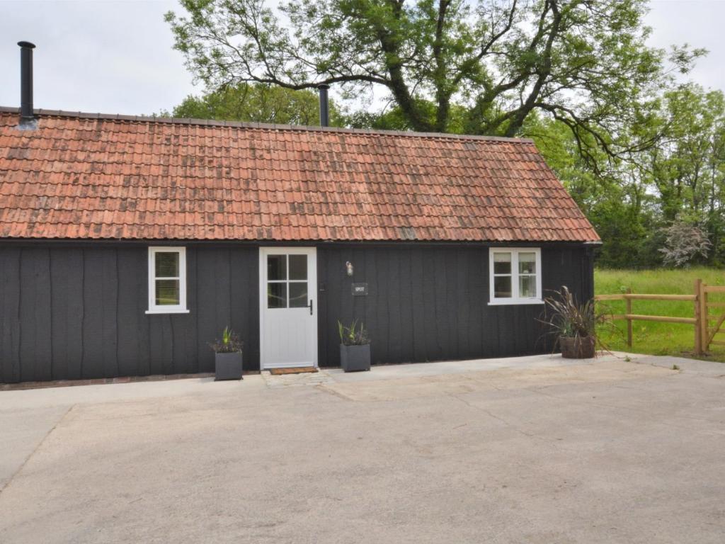a black shed with a white door and a fence at 1 bed in Sherborne 80737 in Wootton Glanville