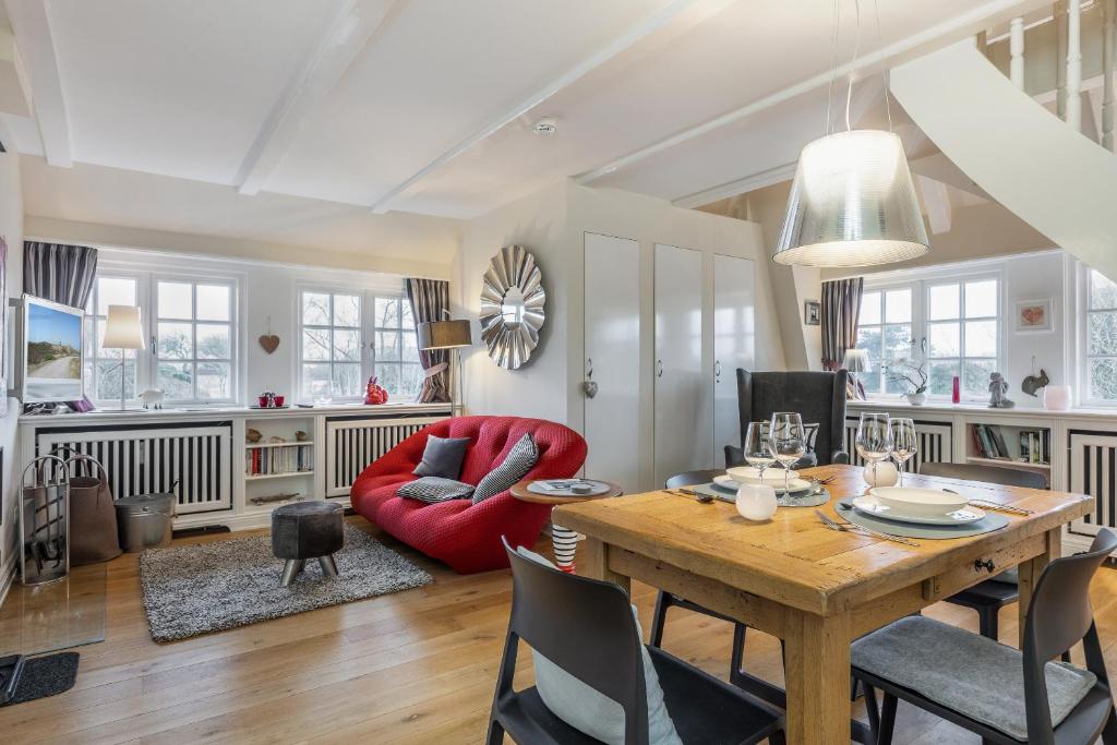 a living room with a table and a red chair at Kleines Nest 40 Wattkueken 41 in Keitum
