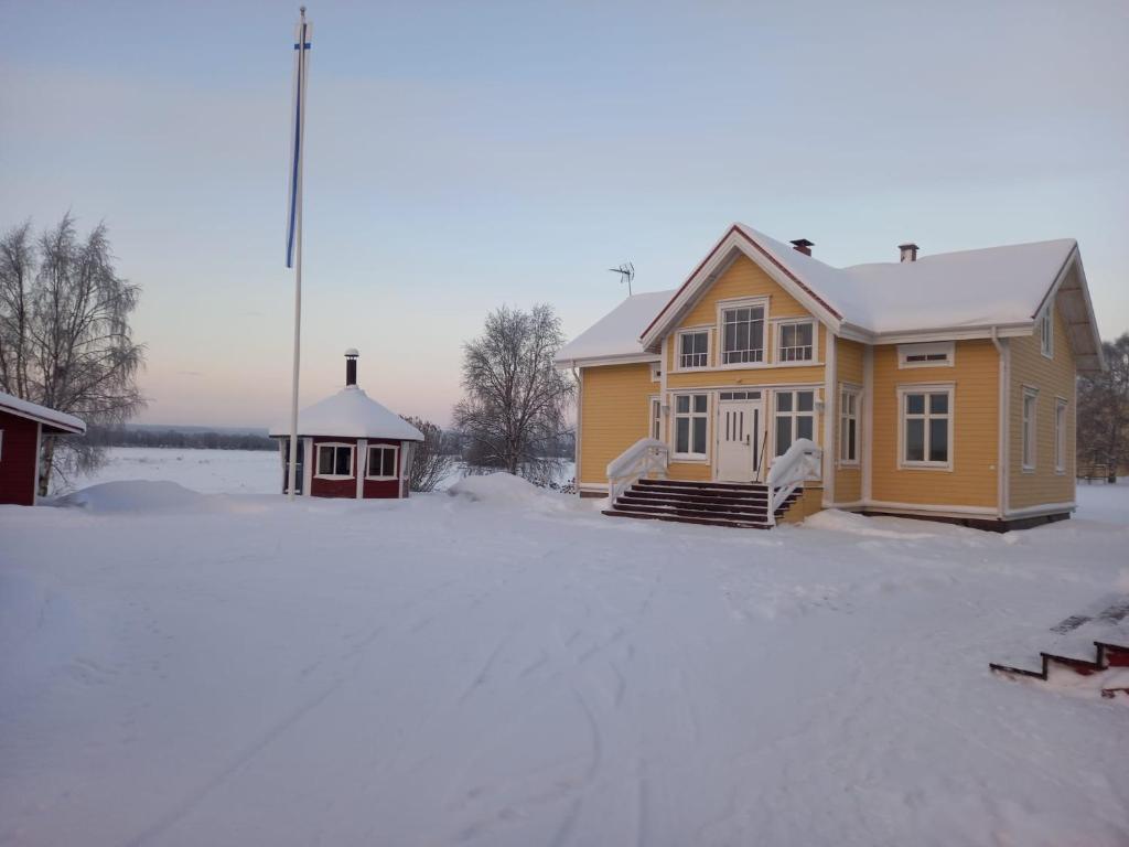 una casa amarilla con nieve en el suelo en Kuivakangas, en Kuivakangas