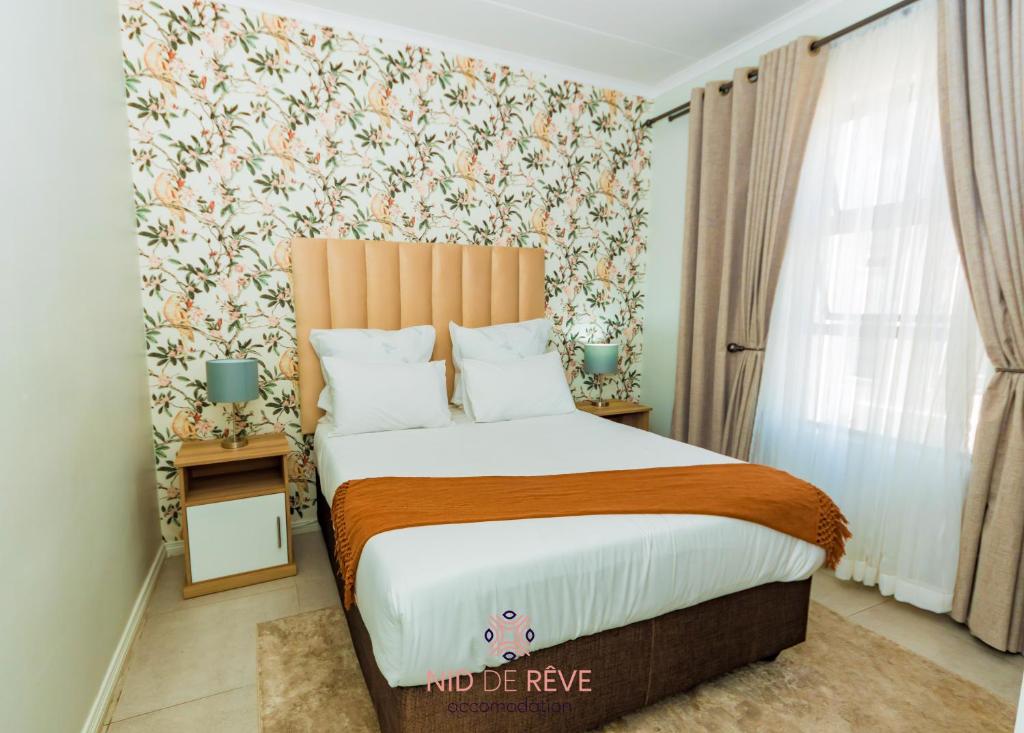 um quarto com uma cama grande e papel de parede floral em Nid de Rêve Accommodation em Midrand