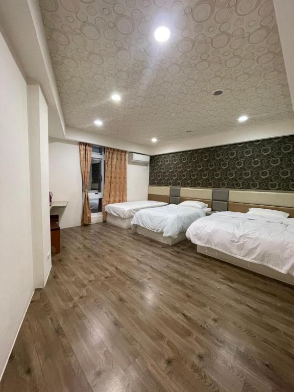 two beds in a room with a wooden floor at Dong Yong Travel in Dongyin/