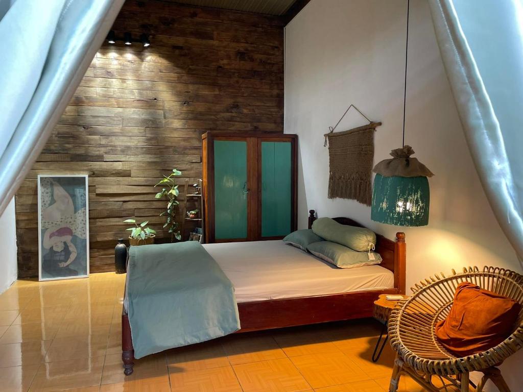 a bedroom with a bed and a chair at Cọ Cùn homestay/Handmade/Artwork in Buon Ma Thuot