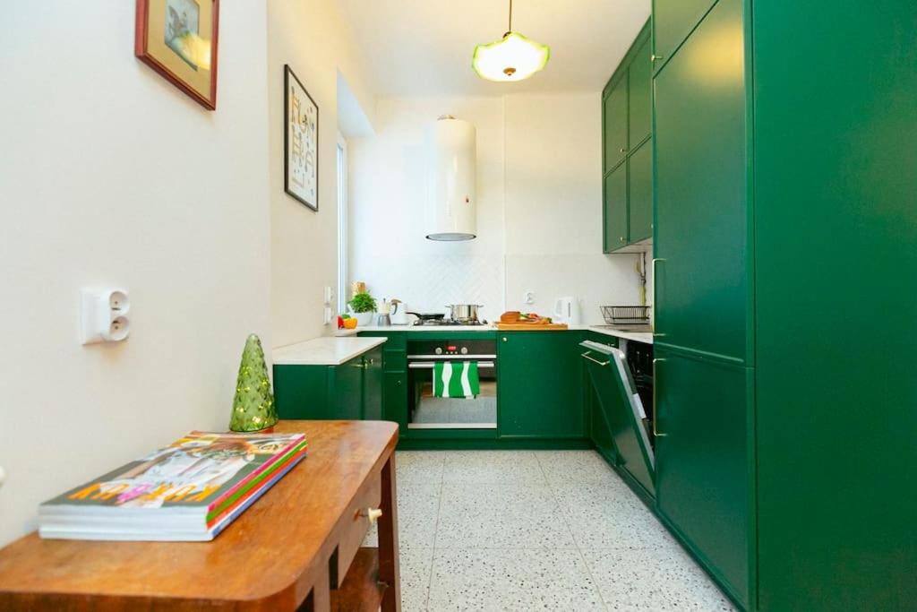 cocina con armarios verdes y mesa de madera en Bright and elegant apartment in the green area!, en Varsovia