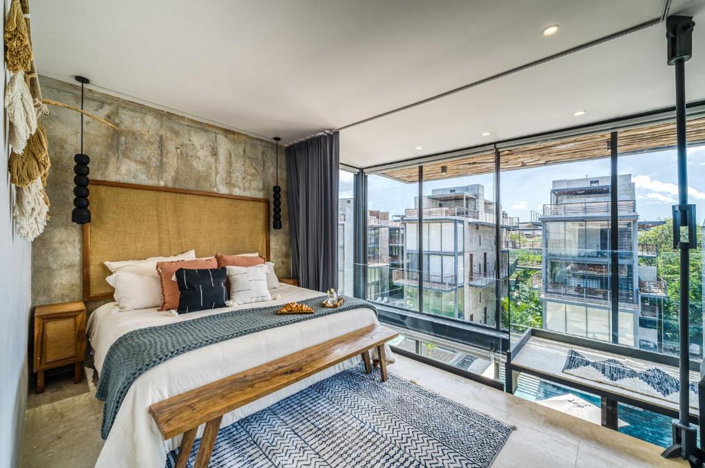 a bedroom with a bed and a large window at Divine 1BR PH Tulum w Private Pool, Cenote, Gym in Tulum