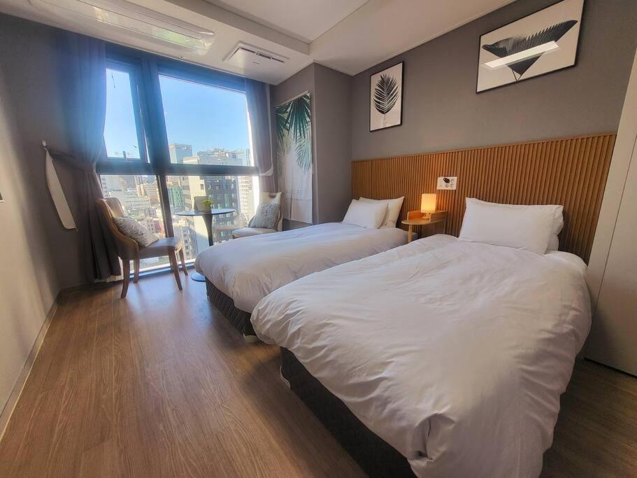 a hotel room with two beds and a large window at Stay C Hotel Myeongdong in Seoul