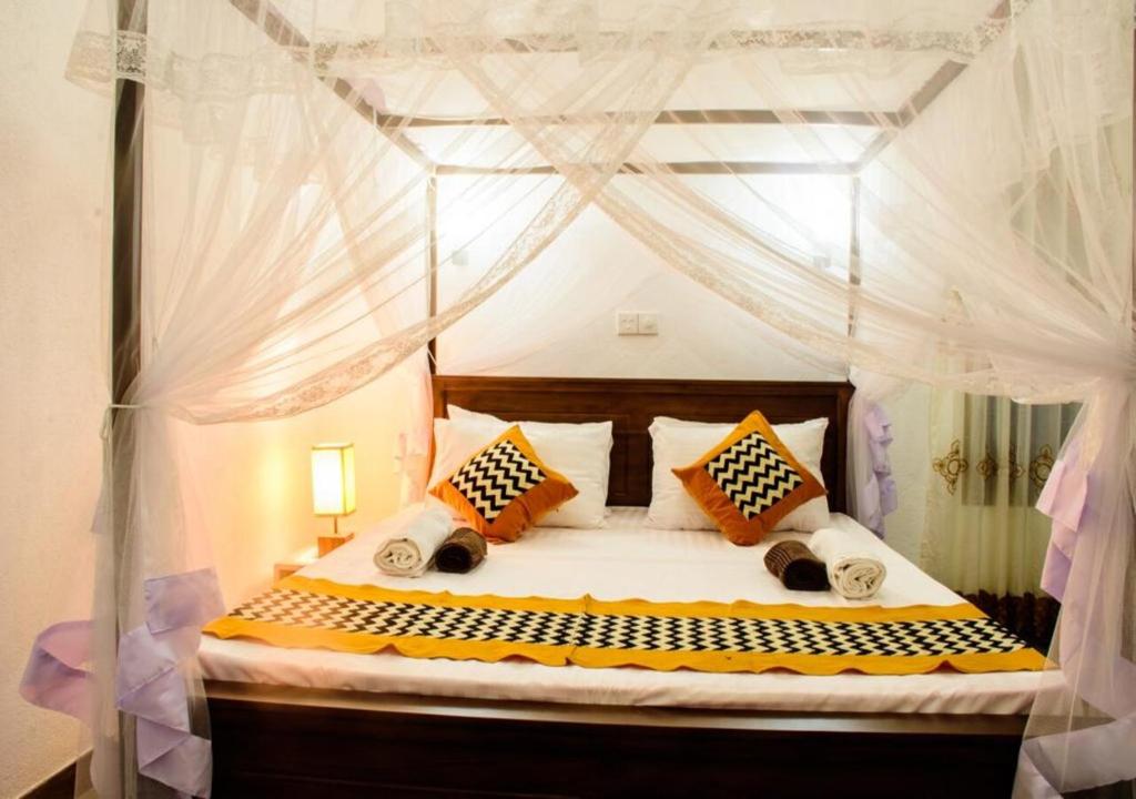 a bedroom with a canopy bed with white curtains at Kurundu Wadiya (Cinnamon Retreat) in Hikkaduwa