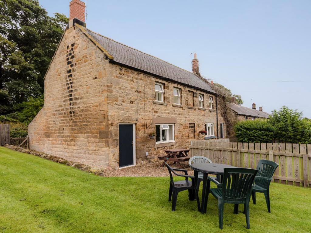 an old brick house with chairs and a table in the yard at Bilton Farm Cottage No1 in Alnmouth