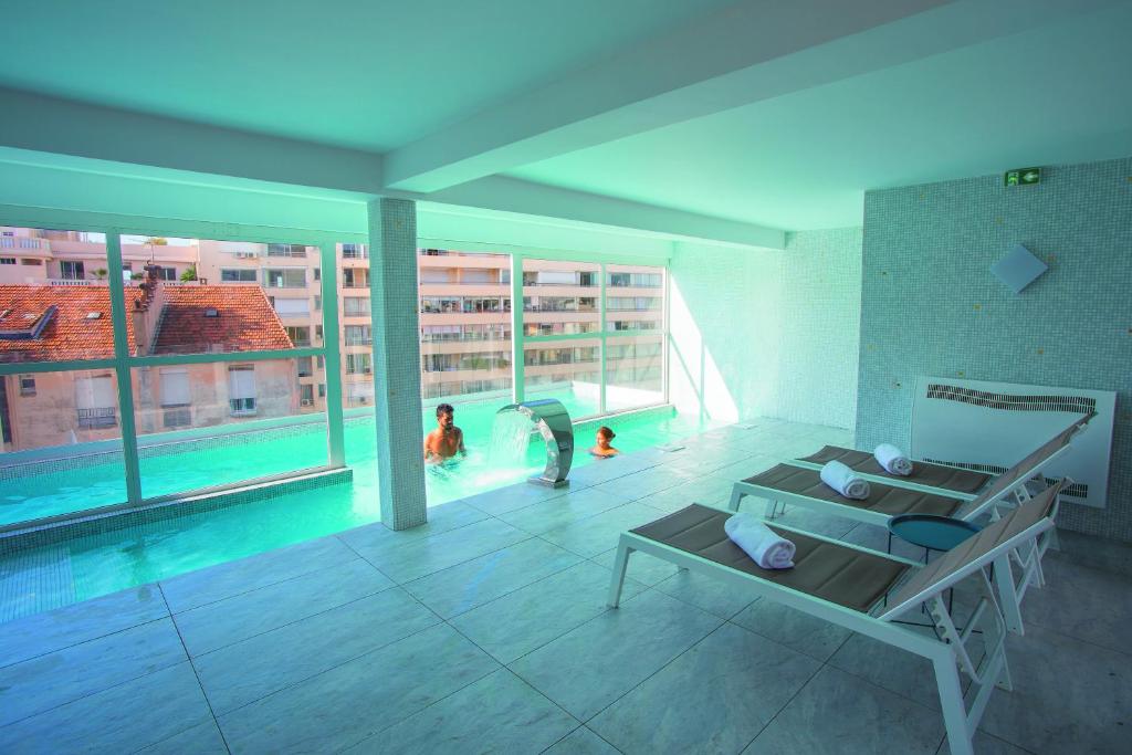 a living room with a pool and people in a building at Cristal Hôtel & Spa in Cannes