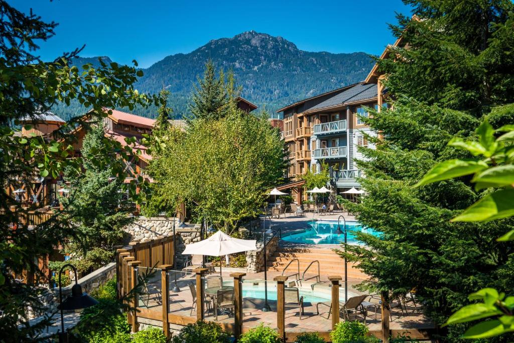 a hotel with a swimming pool and mountains in the background at Legends in Whistler