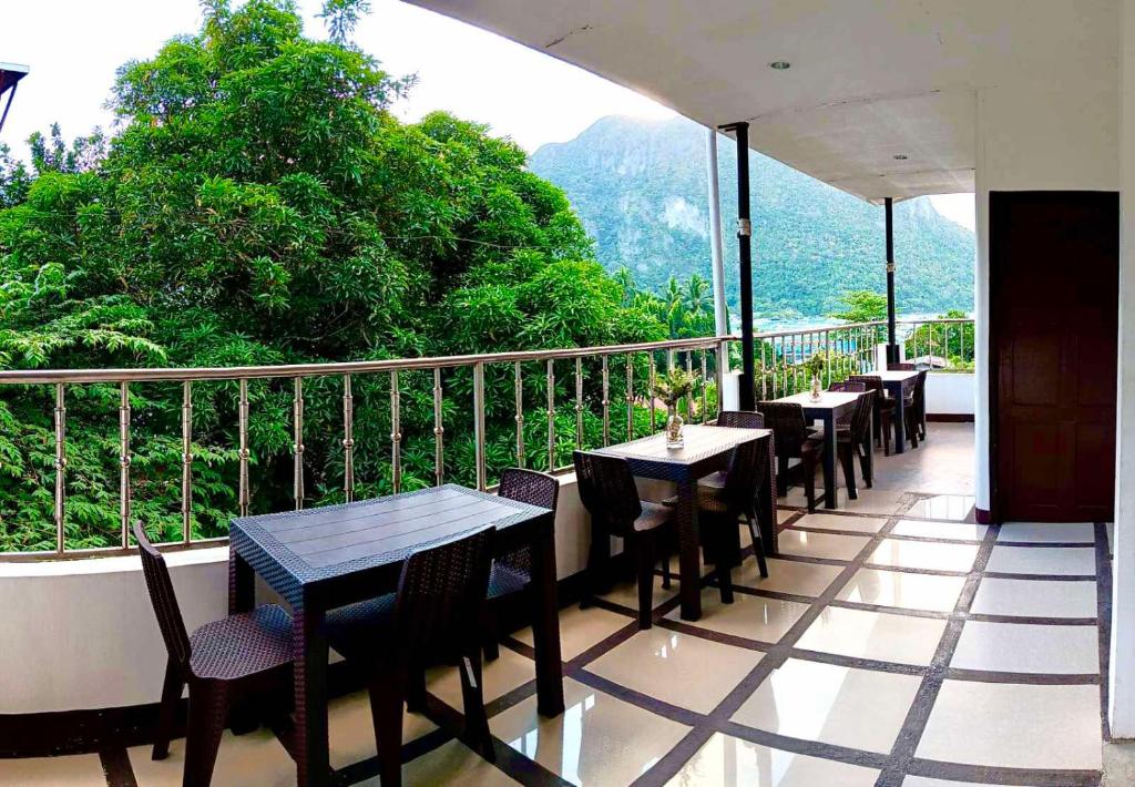 un restaurante con mesas y sillas en un balcón en Forest Bay Inn El Nido, en El Nido