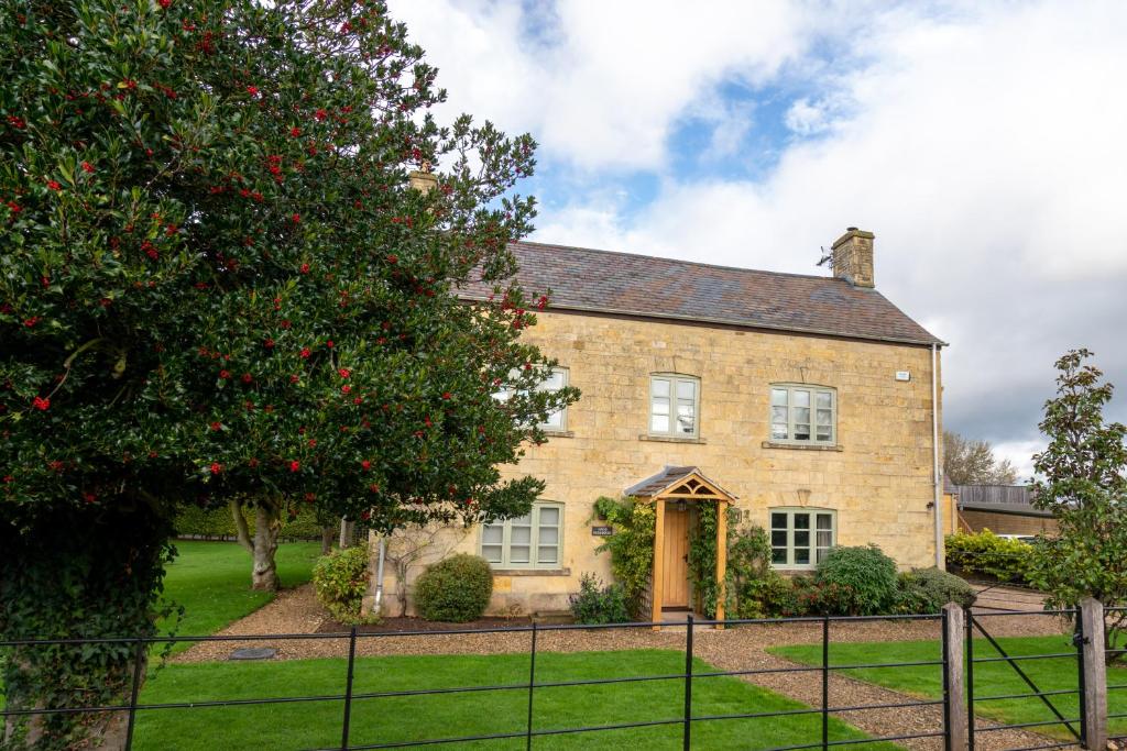 a brick house with a tree in front of it at Pass the Keys - Cotswolds Farmhouse - Sleeps 10 - Stunning garden in Moreton in Marsh