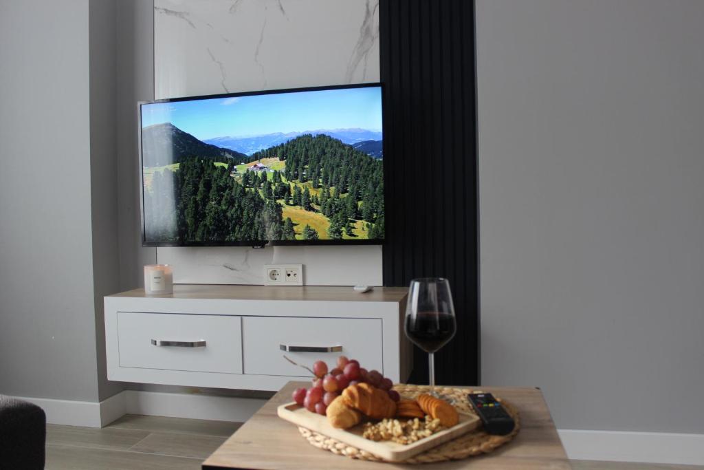 ein Wohnzimmer mit einem Tisch mit einer Schale Obst und einem TV in der Unterkunft Cosy suites hotel in Antalya