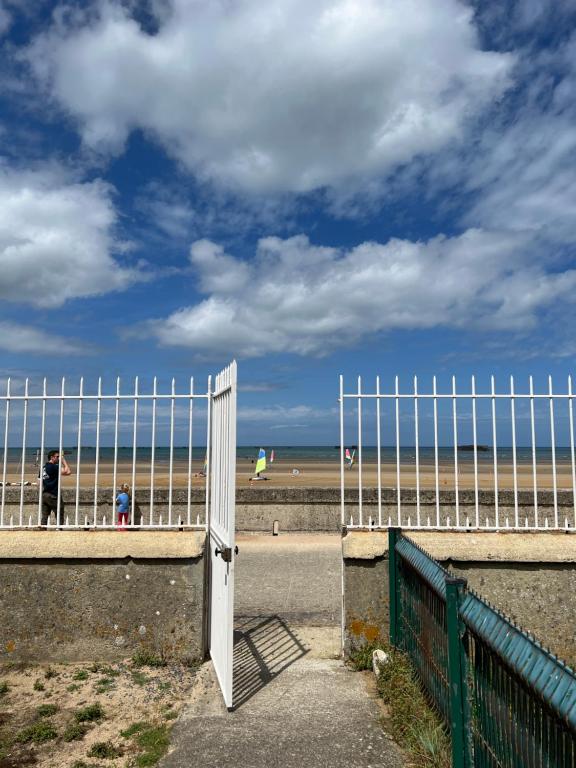 un portail ouvert sur la plage avec une clôture dans l'établissement Sunny Apt on D-Day Beach with Parking, à Saint-Côme-de-Fresné