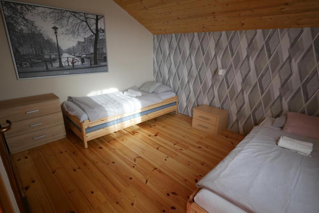 a bedroom with two beds and a wooden floor at Harmónia Vendégház Tahitótfalu in Tahitótfalu