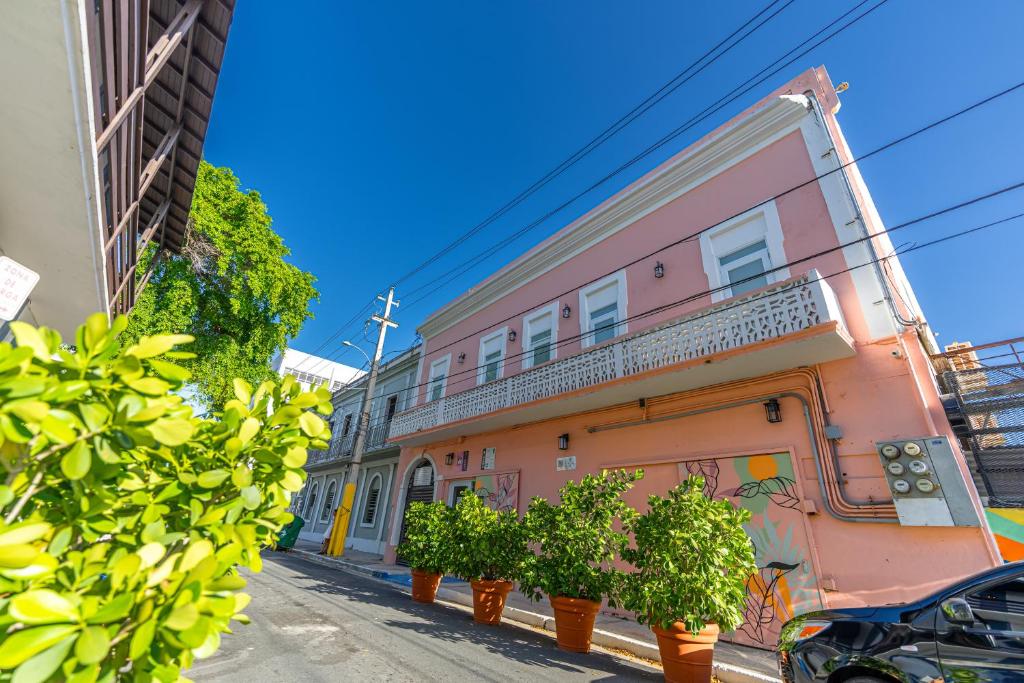 un bâtiment rose avec des plantes en pot dans une rue dans l'établissement Juliette Hostel Digital Nomad Women Only, à San Juan