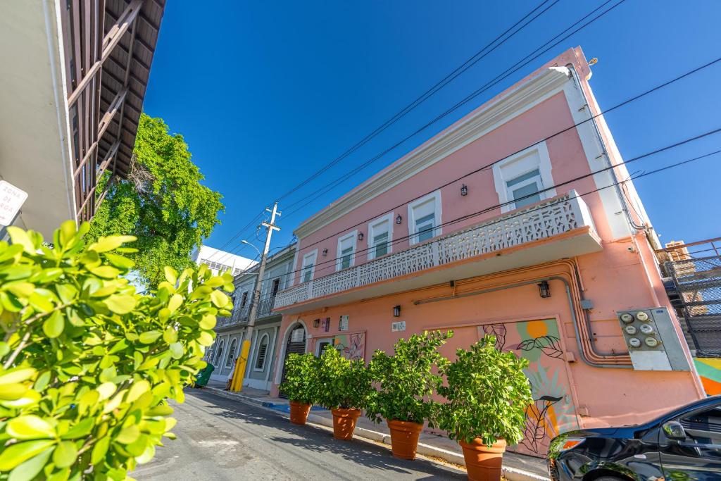 a pink building with potted plants on a street at Juliette Hostel Digital Nomad Women Only in San Juan