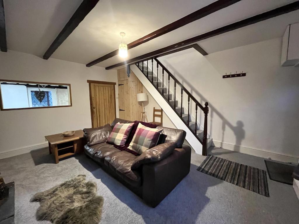 a living room with a leather couch and stairs at Scenic 2 bedroom Cottage in Hill Top