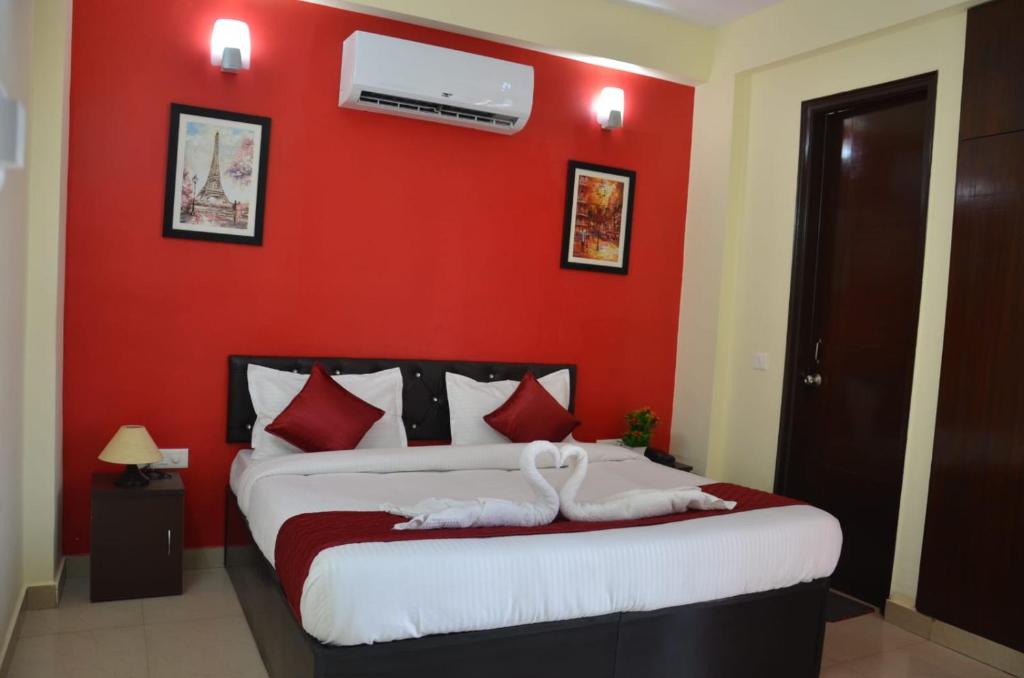 a bedroom with a red wall with a bed at Rumaisa Red in Noida