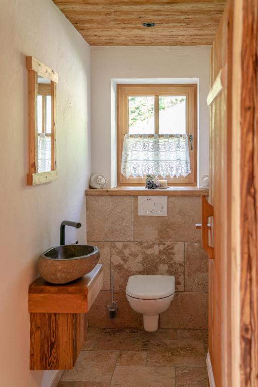 a bathroom with a sink and a toilet and a window at Almchalet Linharterhof in Haus im Ennstal
