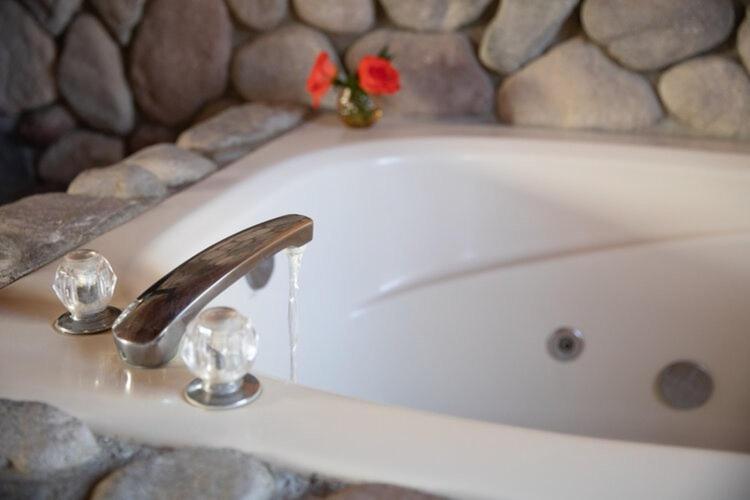 una bañera con un lavabo con una flor roja. en 2401 - Oak Knoll Studio with Jacuzzi #2 cabin en Big Bear Lake