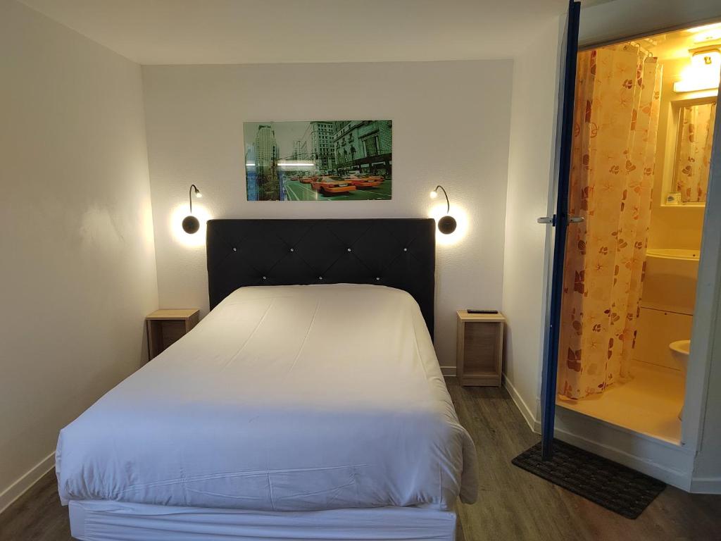 FASTHOTEL PARIS OUEST BOUAFLE في Bouafle: غرفة نوم بسرير ابيض ومرآة