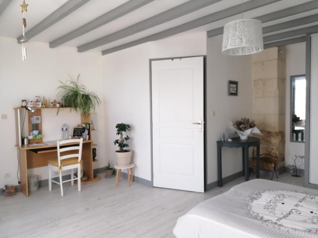 a white bedroom with a bed and a desk and a table at Chez Mado in Thénac
