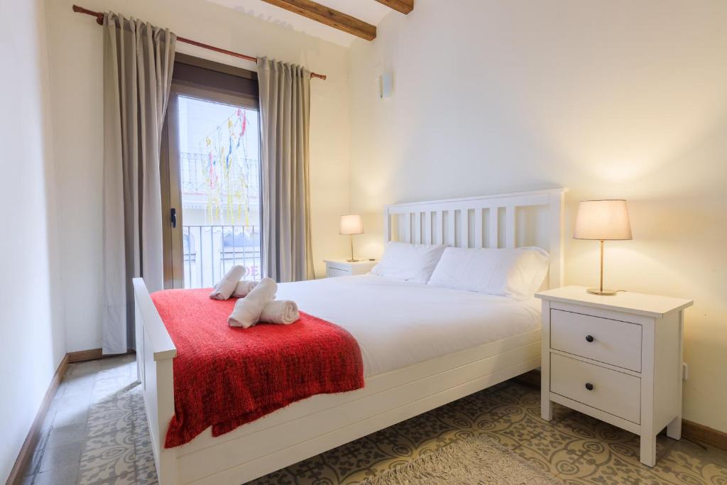 Un dormitorio con una cama blanca con una manta roja y una ventana en Lodging Apartments Gracia, en Barcelona