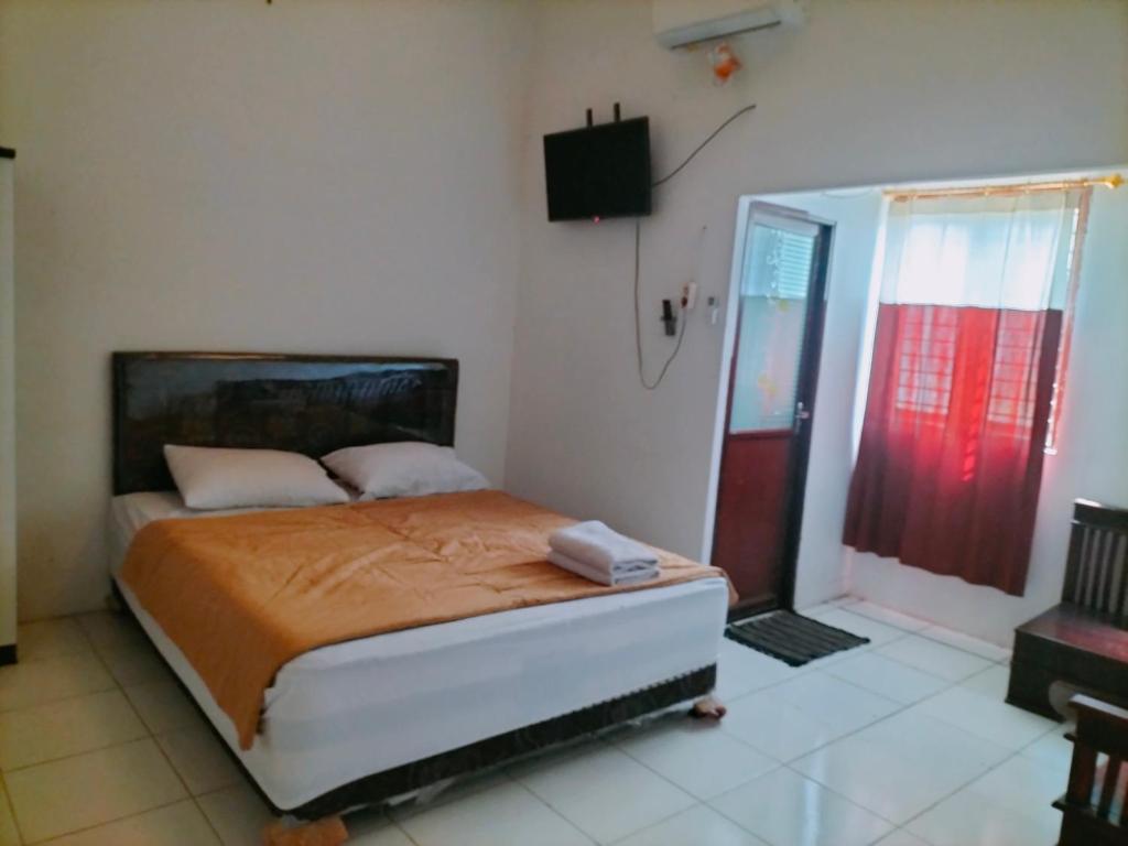 1 dormitorio con 1 cama y puerta roja en Mozza guest house en Klaten