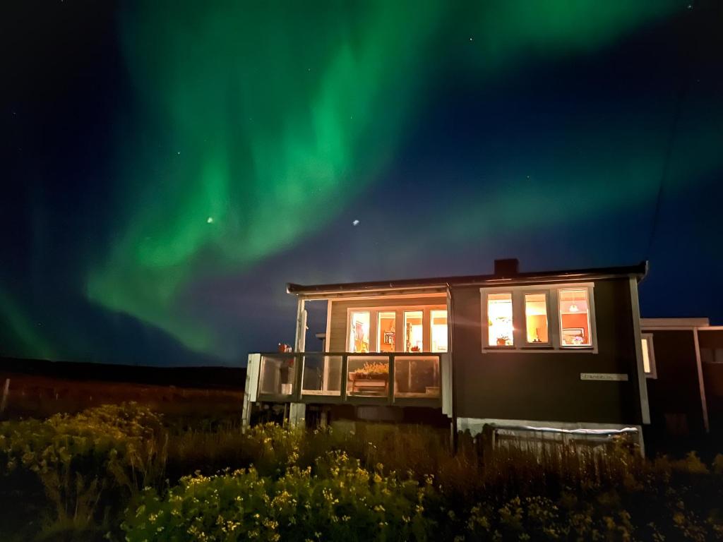 a tiny house with the aurora in the sky at Cape East Homestay in Ytre Kiberg